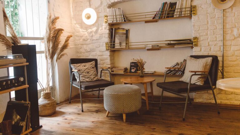 Armchair with table and ottoman in a bright room with white painted brick walls