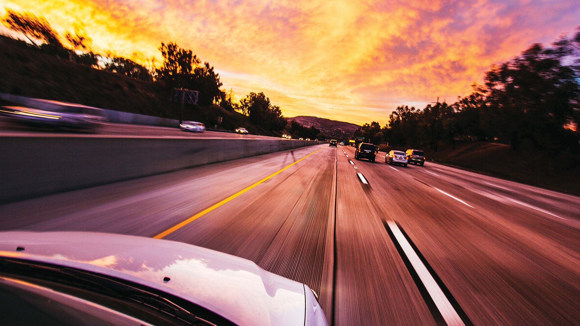 cars ahead on road in sunset