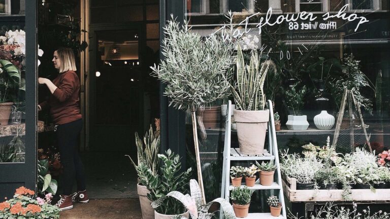 Woman arranging plants in flower shop front