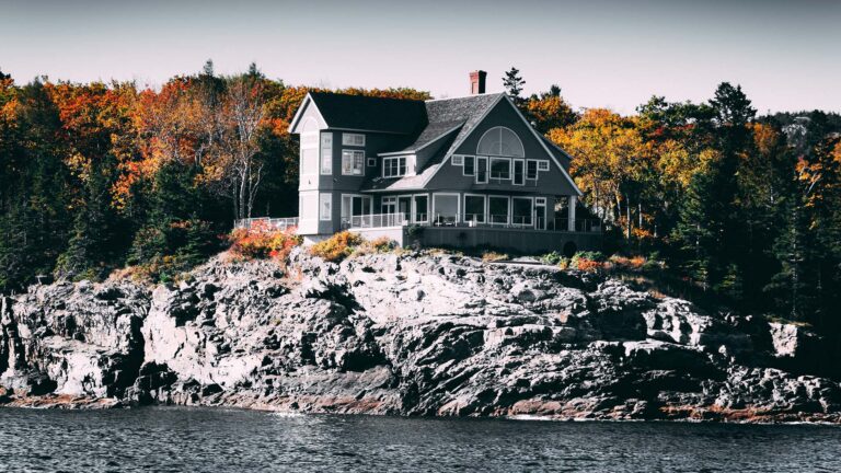 Gray and White House Beside Body of Water on rocks