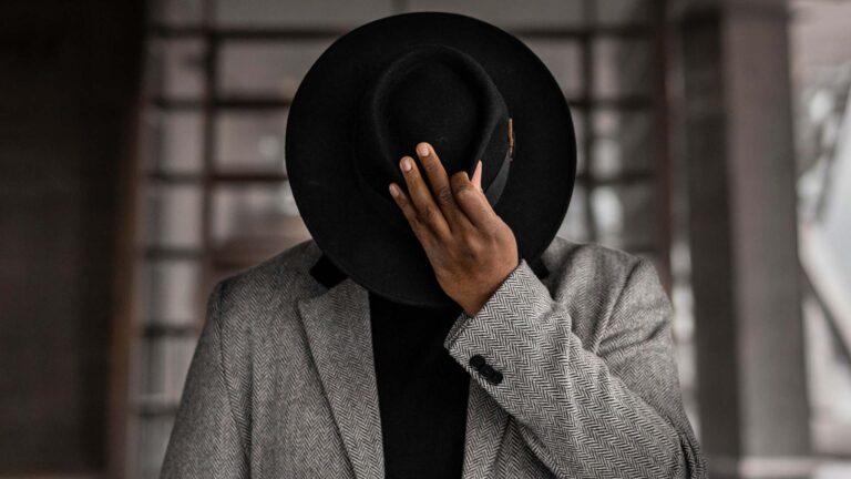 Man looking down holding hat