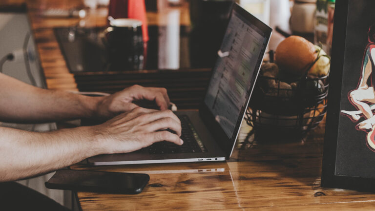 person on laptop sitting on brown table