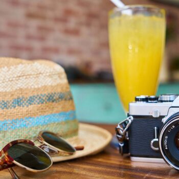 Camera and straw hat sitting on a table on a sunny day