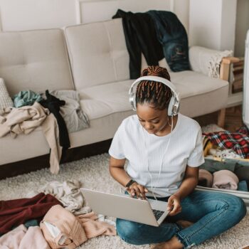 woman using a laptop on the floor wearing headphones