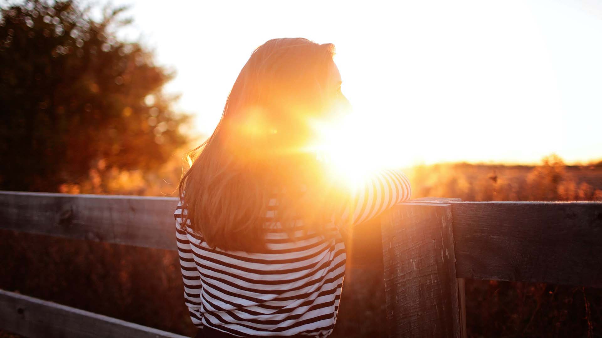 Brunette woman in front of sun