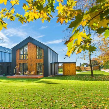 Twin houses of wood and black metal with a large front lawn