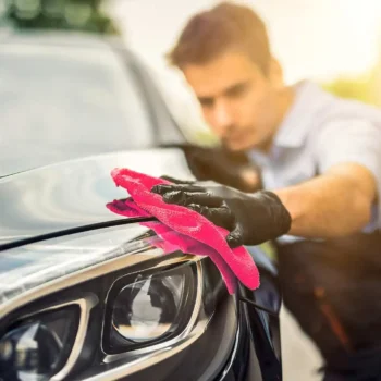 auto detailer wiping down car hood with cloth