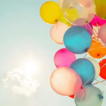 Holding a bunch of balloons in the sky.