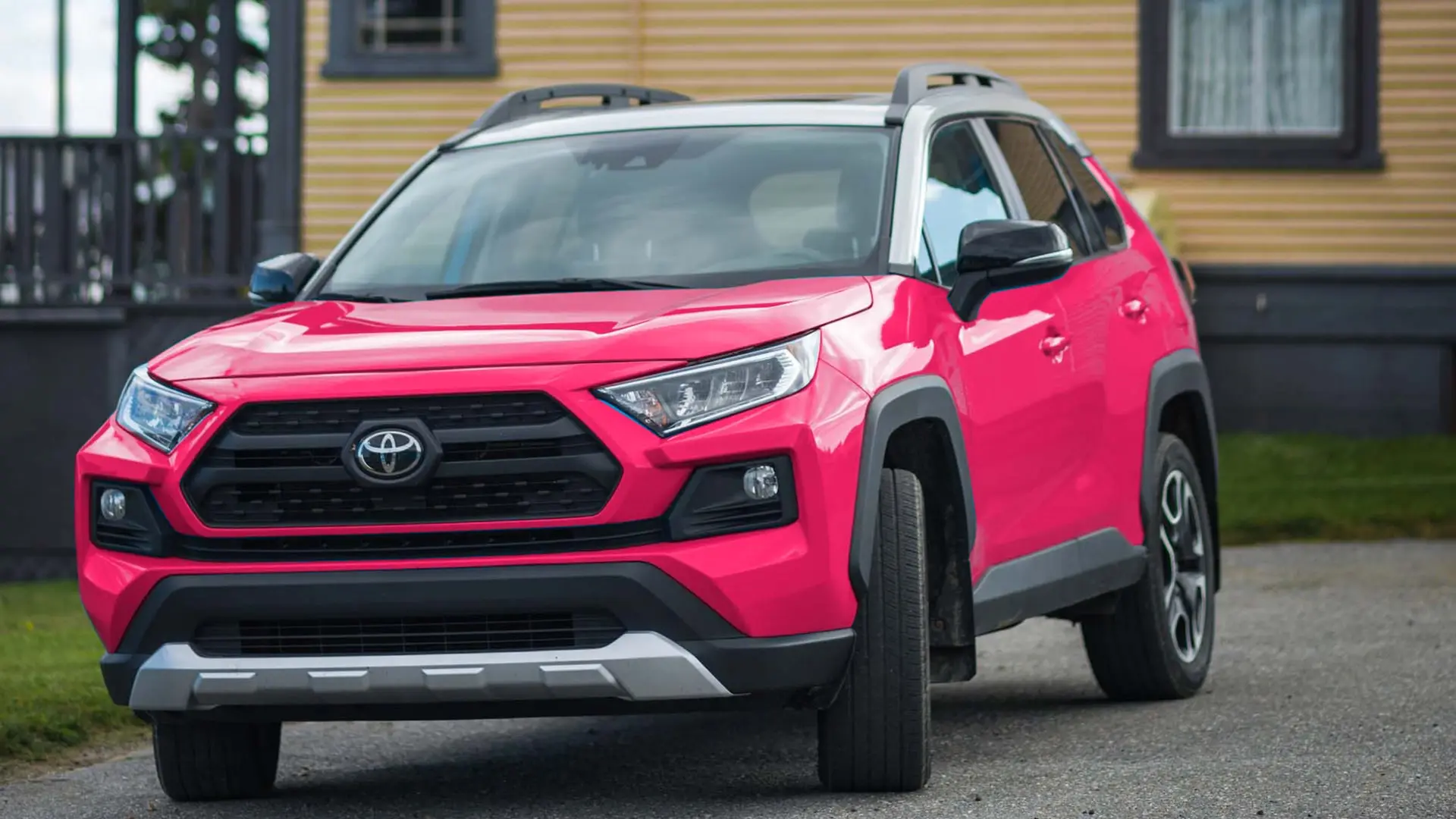 toyota suv in front of yellow house