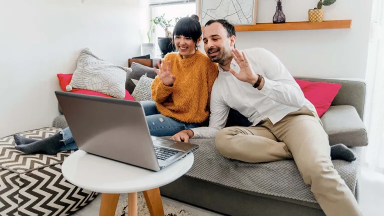 Two people sitting on a couch video calling from their laptop