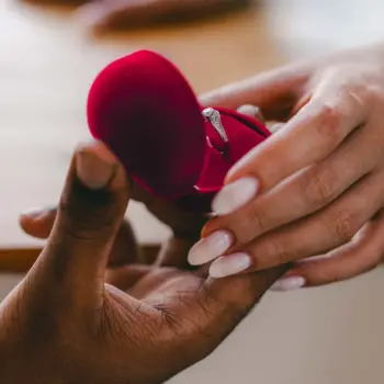 Two hands holding an engagement ring box.