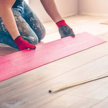 flooring installer laying a piece of laminate flooring