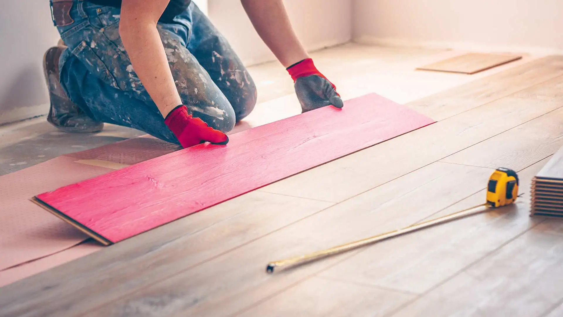 flooring installer laying a piece of laminate flooring