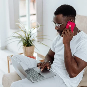 man using phone with laptop on lap