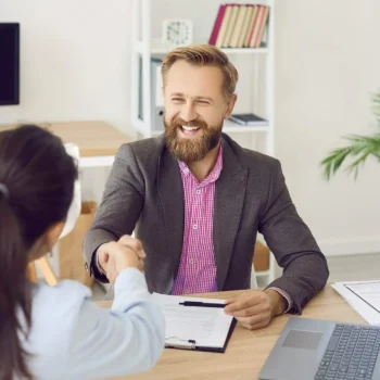 two people in a meeting shaking hands smiling