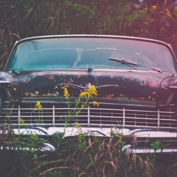 old car in field with grass around it