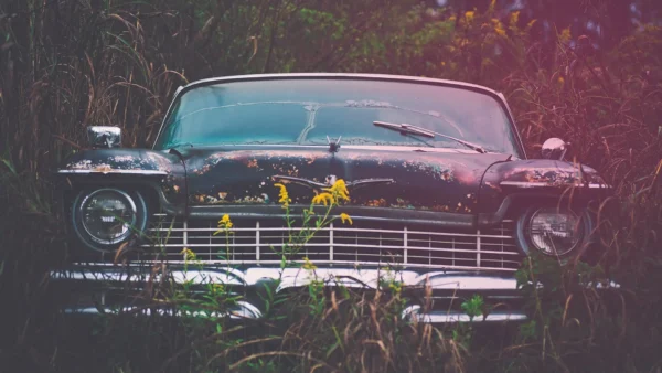 old car in field with grass around it