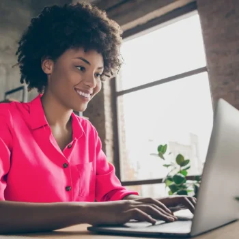 woman sitting in front of laptop reviewing file smiling