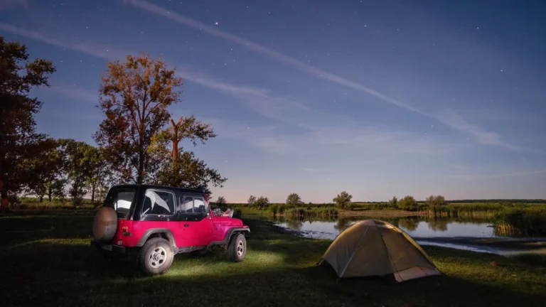 person laying on hood of jeep under stars