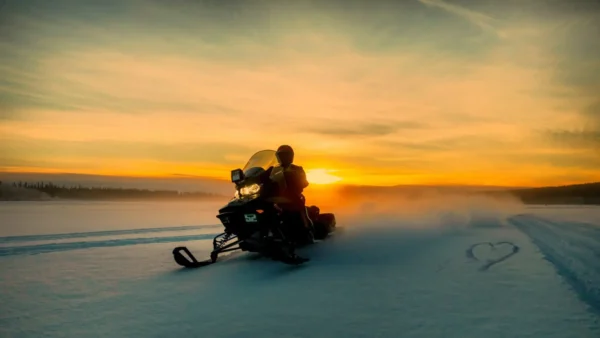 Snowmobile rider driving past a heart in the snow