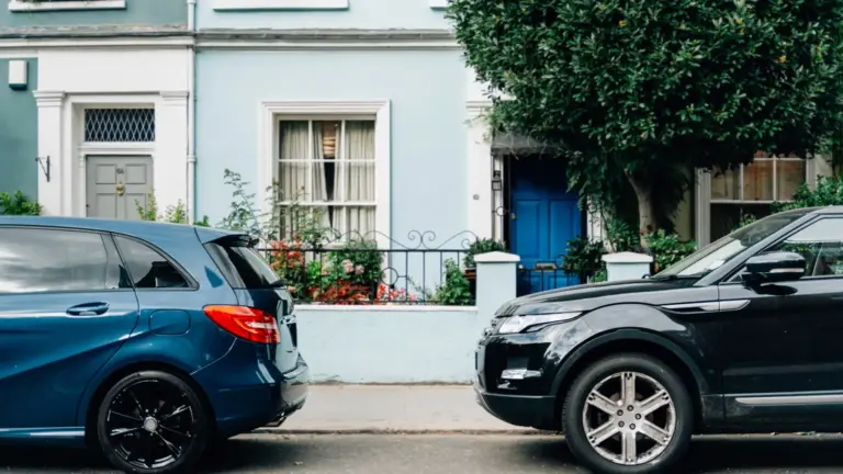 Two cars parked in front of a house.