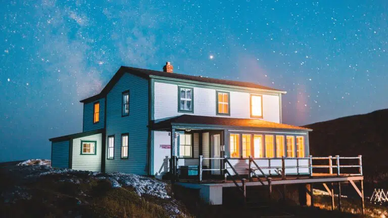 wooden house on a hill under a starry blue night sky